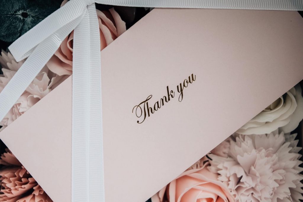 Close-up of thank you card with flowers and ribbon