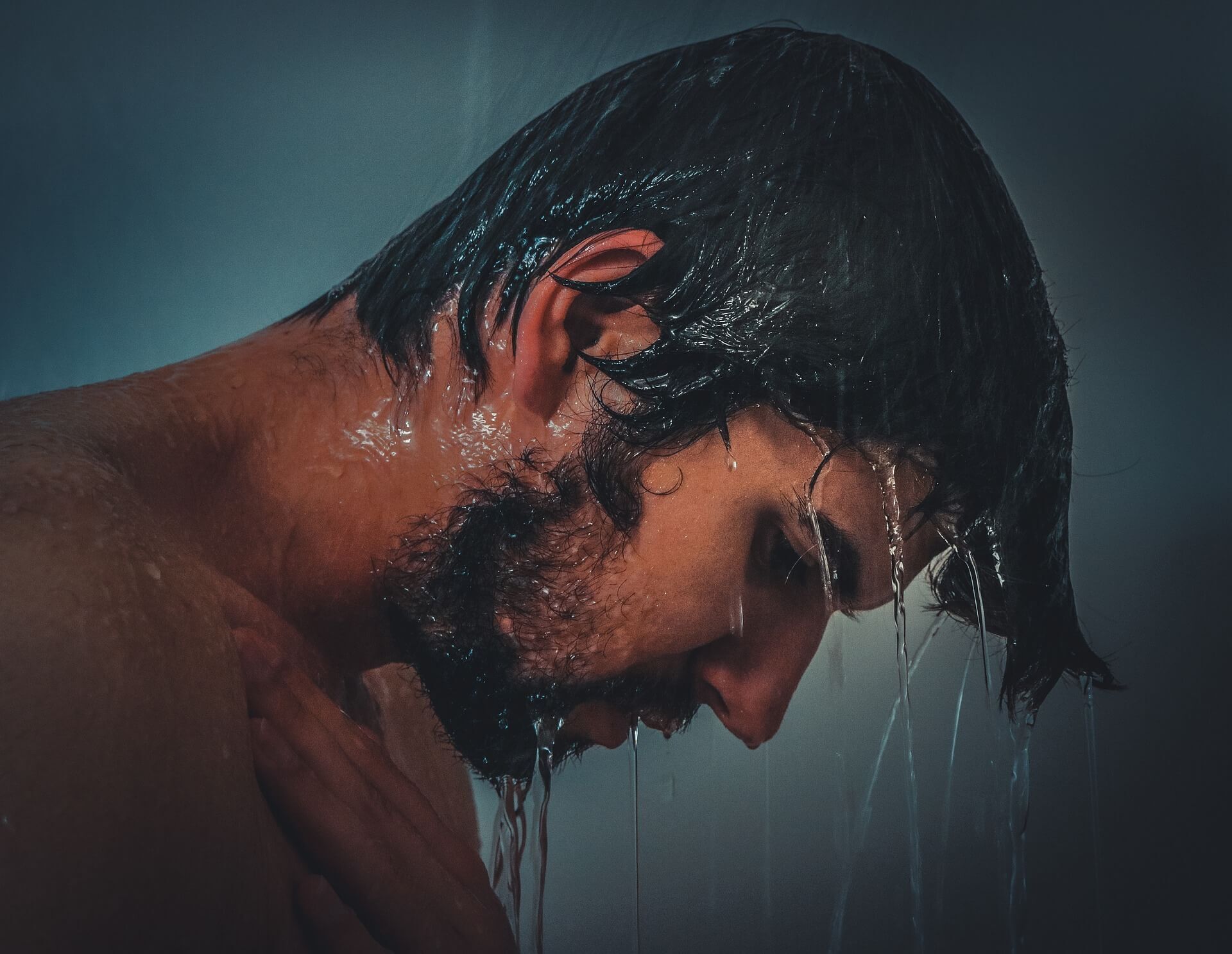 Man with dark hair and beard in shower
